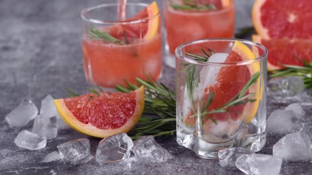ピンクのパロマカクテルでグラスを満たします グレープフルーツとローズマリーのスライスと有機カクテルをリフレッシュします 完璧な夏の柑橘類新鮮な飲み物 — ストック動画