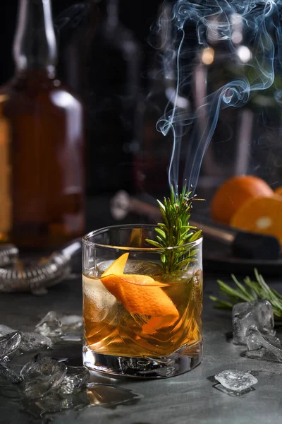 鸡尾酒尾的老时尚黑人 威士忌的口感被糖分所平衡 香草药水和熏香迷迭香增加了风味和原味 配上冰块和橙子 图库图片