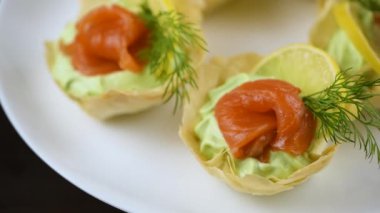 Yumuşak peynirli kremayla çırpılmış avokado en leziz krema, bir dilim somon ve limon. Fırında pilav hamuruyla çıtır çıtır sepetlerde servis ediliyor. Tatil menüsü için mükemmel bir aperatif.
