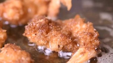 Kızartma tavasında kızgın yağda ekmek kırıntıları içinde taze karides kızartmak. Ekmekli kızarmış karides tarifleri serisinden bir bölüm. Yakın plan, gerçek zamanlı..