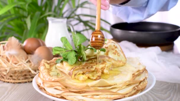 新鲜烘焙的自制薄薄的薄煎饼 薄薄的薄荷糖放在盘子里 配上蜂蜜 一系列视频食谱中的一个 慢动作的圆 — 图库视频影像