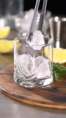 Tonik, limon ve biberiyeli soğuk bir cin kokteyli hazırlıyorum. Dikey video, gerçek zamanlı.