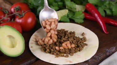 Biftek, fasulye, avokado sosu, lahana ve peynirli taco hazırla. Meksika mutfağı. Yakın plan. Gerçek zamanlı.