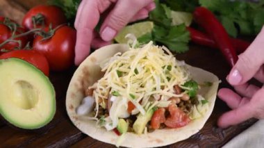 Elimize kıymalı, avokadolu, lahanalı ve peynirli taco alıyoruz. Meksika mutfağı. Yakın plan. Gerçek zamanlı.