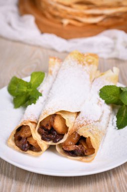 Ev yapımı ince krepler. Elmalar tereyağlı karamel sosunda, kuru üzüm ve tarçınla pişiriliyor ve ince bir krebin içine dolduruluyor. Pudra şekeri ve naneli garnitür. Kaba bir yemek..