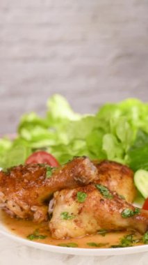 Sarımsaklı, limonlu, fesleğenli, marullu ve sebzeli tavuk budu. Dikey video. Soldan sağa dairesel hareket. Yakın plan.