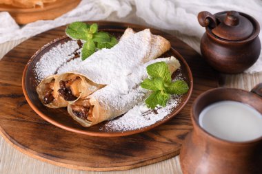 Ev yapımı ince krepler. Elmalar tereyağlı karamel sosunda, kuru üzüm ve tarçınla pişiriliyor ve ince bir krebin içine dolduruluyor. Pudra şekeri ve naneli garnitür. Kaba bir yemek..