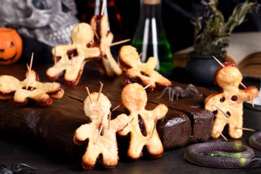 Voodoo cookies made of puff pastry with jam and pierced with wooden skewers. Idea for the Halloween party clipart