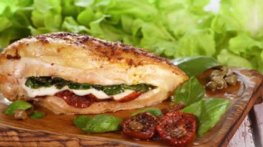 Ispanak, kurutulmuş domates ve mozzarella ile doldurulmuş çıtır çıtır tavuk göğsü, ahşap bir tabakta servis ediliyor. Yavaş çekim, yatay hareket soldan sağa