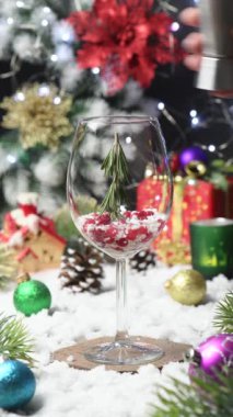 Noel Kar Küresi Kokteyl Tarifi. Biberiye, kızılcık, cin ve tonik iki pipetli Noel ağacı. Mükemmel bir tatil içkisi. Şarap bardağında servis edilmiş. Gerçek zamanlı. Dikey Video