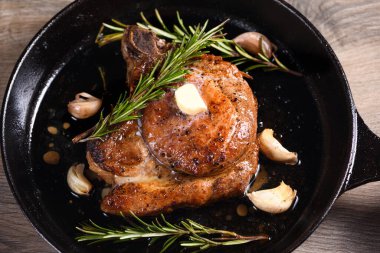 Kemiğin üzerinde domuz pirzolası bir parça tereyağında sarımsak ve biberiyeyle kızartma tavasında. 