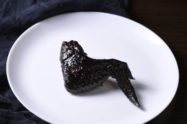 Yarasa kanatları. Tabakta mürekkep balığı mürekkebiyle tatlı ve ekşi sosta pişirilmiş. Cadılar Bayramı partisi için orijinal bir fikir.