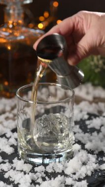 Kokteyl hazırlıyorum. Isınmış burbon, taze limon ve portakalla karıştırılmış baharatlı biberiye şurubu. Bourbon Old Fashioned, Noel aromalı bir kokteyl. Dikey video. Gerçek zamanlı.