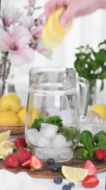 Çilekli, böğürtlenli ve naneli Summer Limonade yapıyorum. Gerçek zamanlı dikey video. Yakın plan.