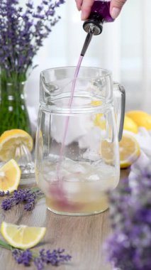 Lavanta şurubu, limon suyu ve lavanta filizi ile köpüklü su ile ev yapımı limonata yapıyorum. Dikey video, gerçek zamanlı. Yakın plan.