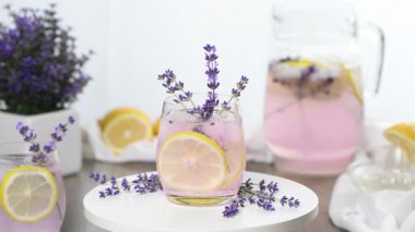 Ev yapımı lavantalı limonata. Limon dilimleri ve lavanta filizi ile süslenmiş. Yatay video. Yakın plan. Dairesel hareket, sağdan sola