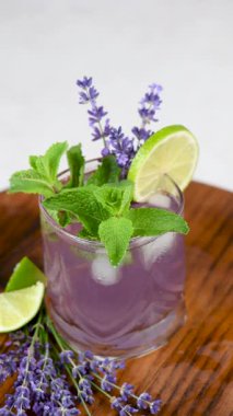 Lavantalı mojito kokteyli, lavanta şurubu, limon suyu, tonikli tekila, lavanta filizi ve nane. Dikey video. Yakın plan. Dairesel hareket