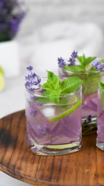 Lavantalı mojito kokteyli, lavanta şurubu, limon suyu, tonikli tekila, lavanta filizi ve nane. Dikey video. Yakın plan. Dairesel hareket