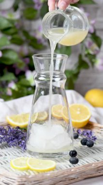 Lavanta, limon suyu, lavanta şurubu ve yabanmersinli yaz limonatası yapıyorum. Dikey video. Gerçek zamanlı. Yakın plan.