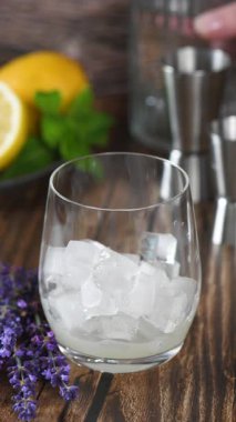 Aynı şekilde lavantalı lavanta kokteyli yapalım. Limon suyu, tekila ve tonik. Bir tutam lavanta ve naneli garnitür. Dikey video. Gerçek zamanlı. Yakın plan.