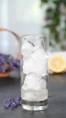 Lavantalı lavanta şurubu, limon suyu, tekila ve tonik ile yaz kokteyli yapalım. Bir lavanta filizi ve bir dilim limonla garnitür. Dikey video. Gerçek zamanlı. Yakın plan.