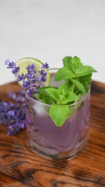 Lavantalı mojito kokteyli, lavanta şurubu, limon suyu, tonikli tekila, lavanta filizi ve nane. Dikey video. Yakın plan. Dairesel hareket