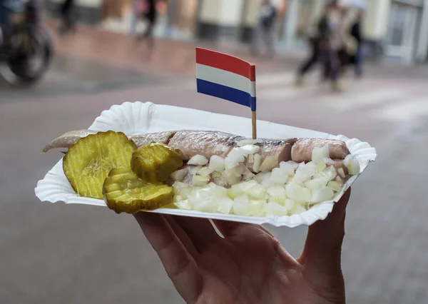 アムステルダムのストリートフード 魚の漬物 玉ねぎ オランダ国旗と塩水ニシン アムステルダムのスナックでまだ生活 ソフトフォーカス ストック画像