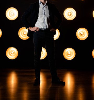 Koyu renkli bir odada beyaz gömlekli, ceketli, tanınmayan şık bir adam..