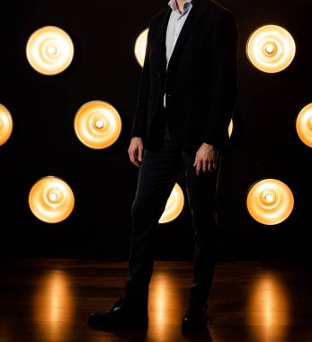 Koyu renkli bir odada beyaz gömlekli, ceketli, tanınmayan şık bir adam..