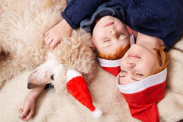 Son with mother and dog are hugging while lying on the sofa in new year, christmas.