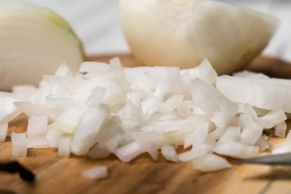 Diced onion on a wooden cutting board. Sliced white onion.