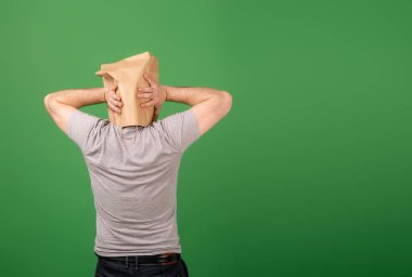 Kafasında kese kâğıdı olan tanınmayan bir adam yeşil arka planda kafasını tuttu. Mesajın için yer aç. Ruh sağlığı, yeşillik, yanlış bilgilendirme kavramı