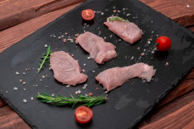 Biberiyeli ve kaba tuzlu siyah taş zemin üzerinde çiğ hindi filetosu..