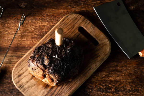 Bir parça pişmiş et. Ahşap bir tahtanın üzerinde fırında pişirilmiş baharatlı domuz eti..