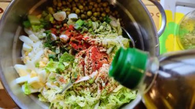 A fresh vegetable salad. Adding olive oil. Salad of Savoy cabbage, eggs and peas with spices.