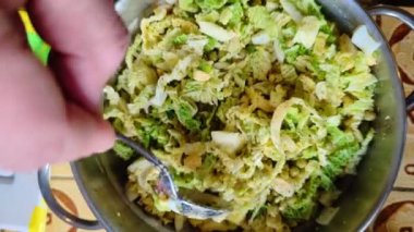 A fresh vegetable salad. Stirring with a spoon. Salad of Savoy cabbage, eggs and peas with spices.