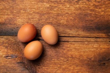 three chicken whole eggs on a wooden surface. Place for text.