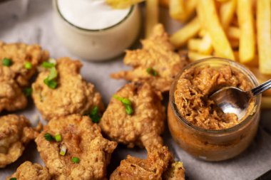 Cauliflower wings food. Pieces of cauliflower cooked in batter on a plate on a wooden background. Sprinkled with green onions.