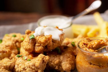 Cauliflower wings food. Pieces of cauliflower cooked in batter on a plate on a wooden background. Sprinkled with green onions.