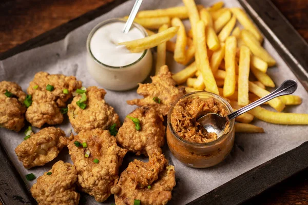 Cauliflower wings food. Cauliflower pieces and french fries with vegan sauces. Vegetarian food.