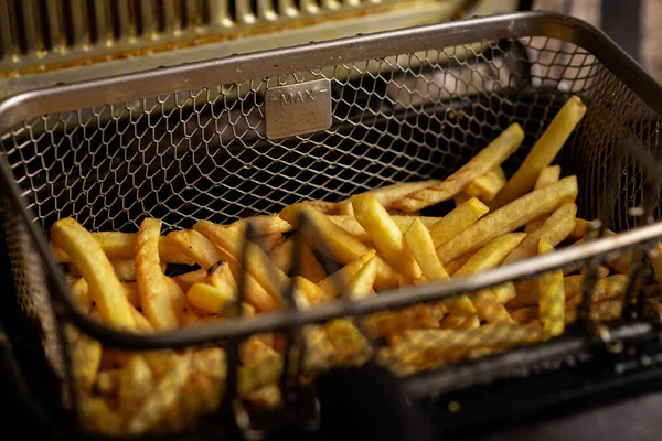 Cooking potatoes in a deep fryer. French fries are removed from the oil.
