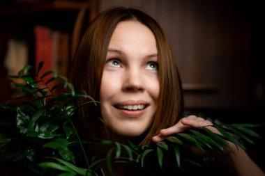 Yeşil bitkiler içinde gülümseyen orta yaşlı bir kadının portresi. Kırklı yaşlarda bir kadın. Rahatlama, sakinleşme, mutlu yüz..