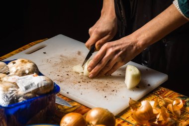 Kesme tahtasında dilimlenmiş beyaz soğan. Kadınların elleri yemek yaparken soğan kesiyor..