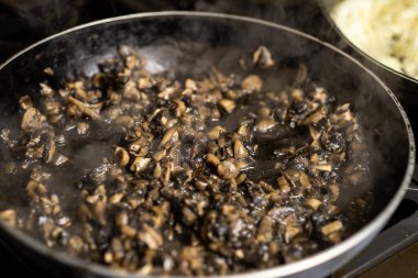 Tavada mantar kızartmak. İyi doğranmış şampiyonlar pişti. Buhar geliyor..