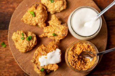 Cauliflower wings food. Pieces of flour-fried cauliflower with vegan sauces on a plate. Wooden background. Vegetarian food.