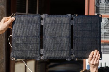 Portable solar battery in male and female hand. Charging mobile gadgets in nature without electricity. Alternative energy source concept.
