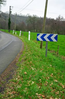 Road and road sign warning about a turn in the road. Road safety concept. An arrow sign indicating a left turn in the road.