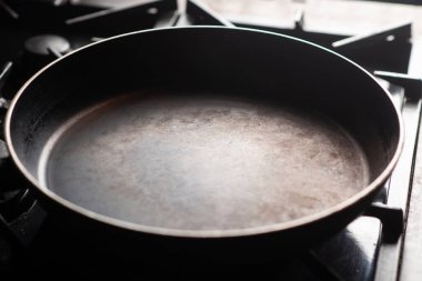 Empty pan on the stove. An old frying pan is heated in a home kitchen.