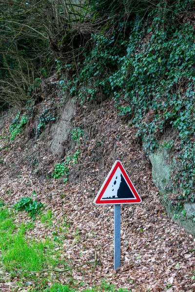 Road sign warning about falling stones near the mountain. Vertical orientation.