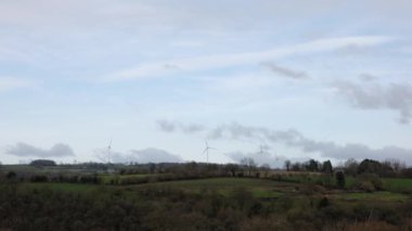 Fields and hills and working windmills in the distance. Calm countryside.